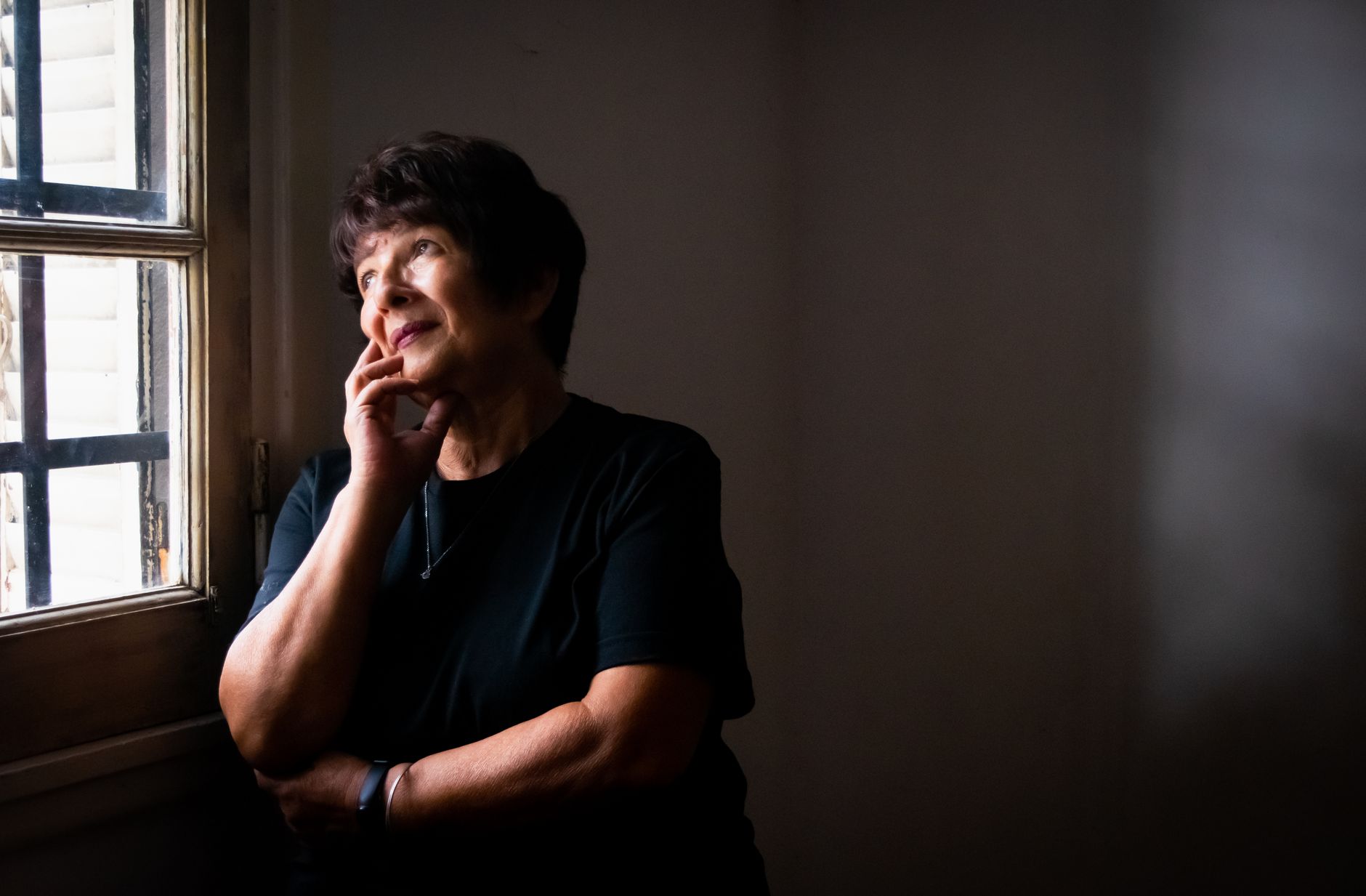 A senior woman sitting thoughtfully near a window