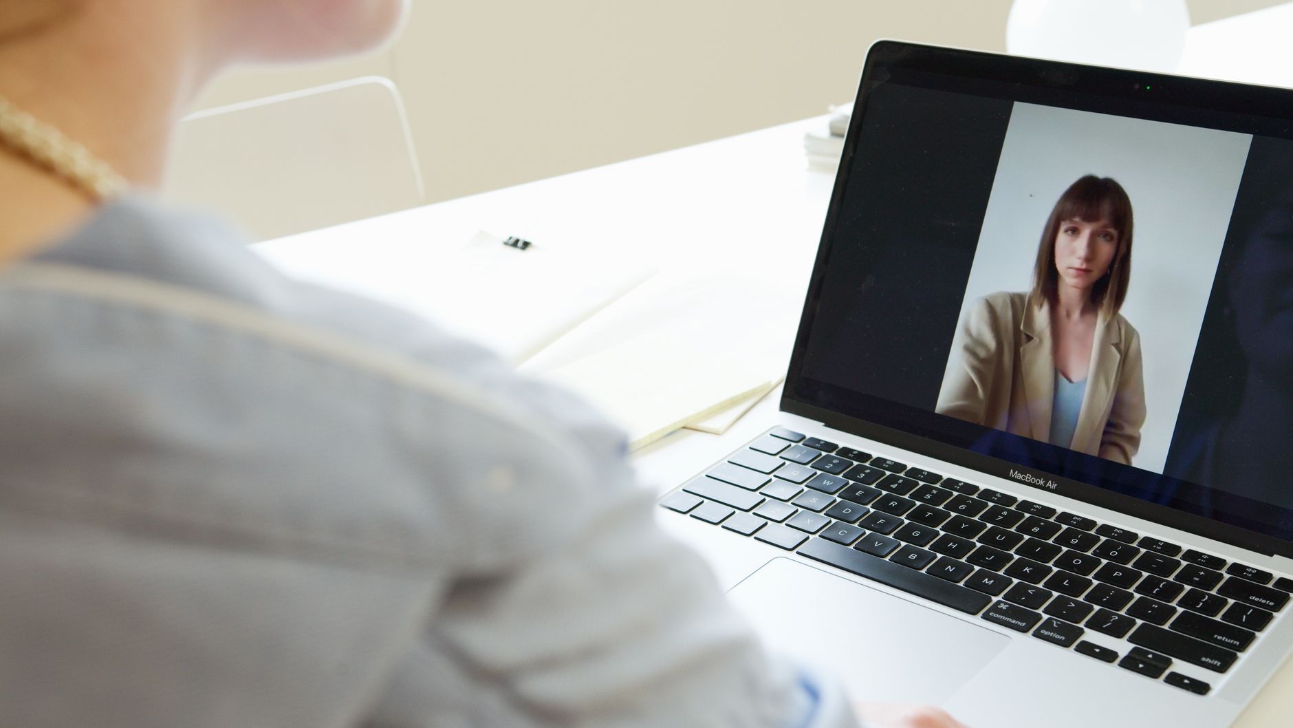 A person on a laptop video call at a home desk