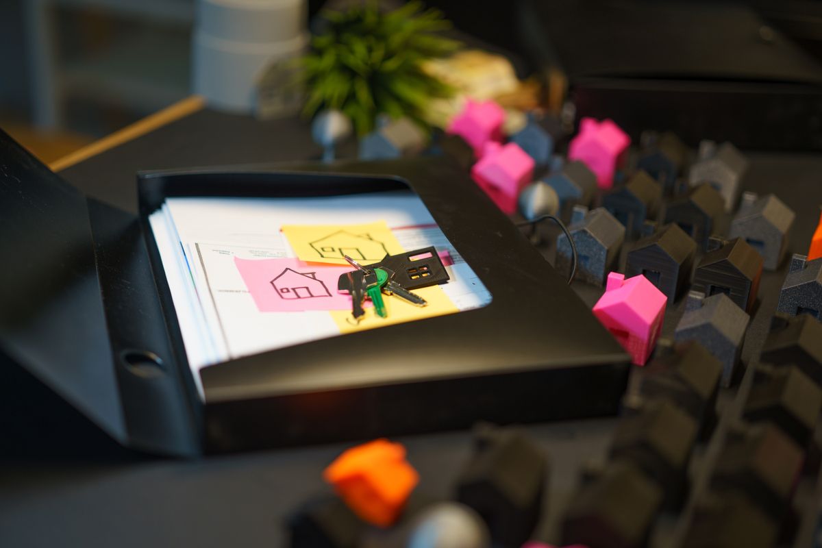House keys resting on real estate documents beside small model houses