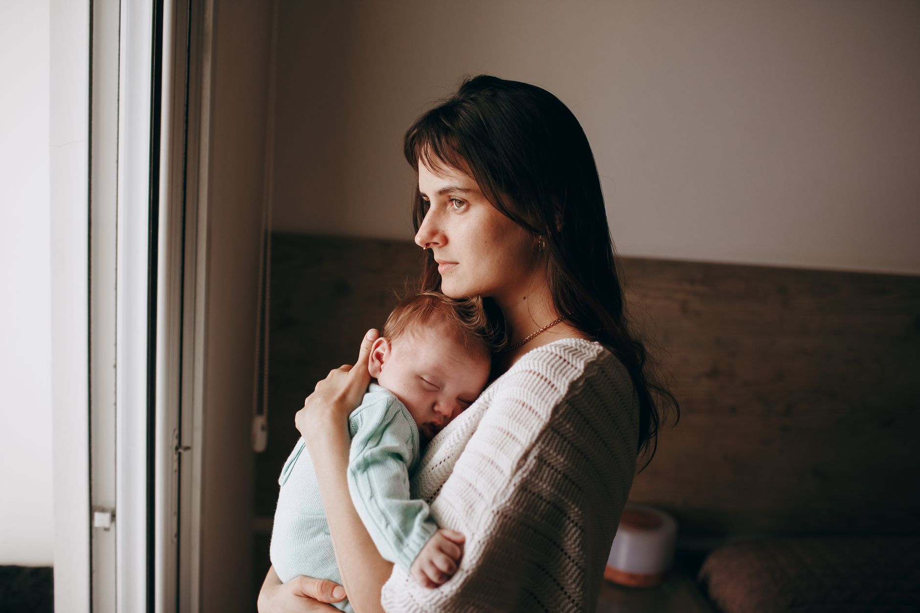 A parent holding a sleeping newborn at home