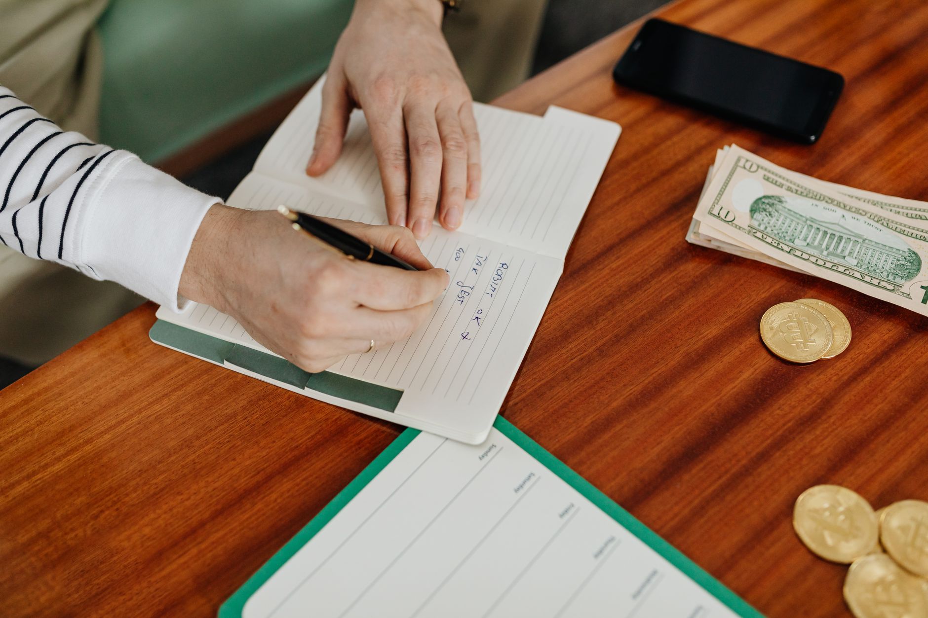 A ledger and pen laid out on a wooden desk