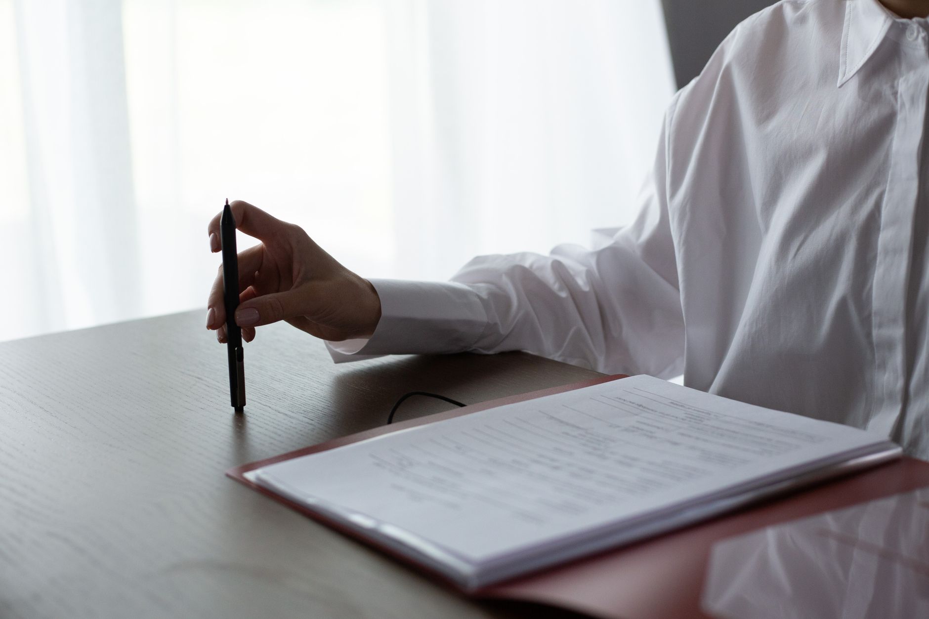A person closely reviewing a contract at a desk